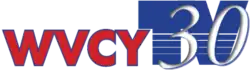 In red, the station's call letters, "WVCY", are rendered in red with black edging. Next to it, a stylized thick blue logo reading "TV" appears with several lines in the bottom portion. WIthin the TV logo, a white and italicized serifed "30" appears.