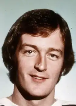 caucasian male in his early 30s with brown hair that covers his ears