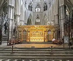 A golden altar and screen in the centre of a grey stone church