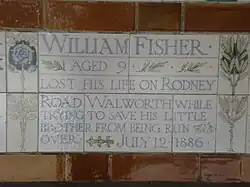 A tablet formed of five tiles of varying sizes, bordered by yellow and blue flowers in an art nouveau style
