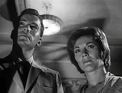 Shatner and Jeanne Cooper are looking beyond the camera in a stern manner.