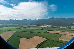 Blue sky with large clouds, with vast fields in the ground.