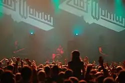 Zoot Woman live in concert, performing amidst fog and red lighting in front of a large audience